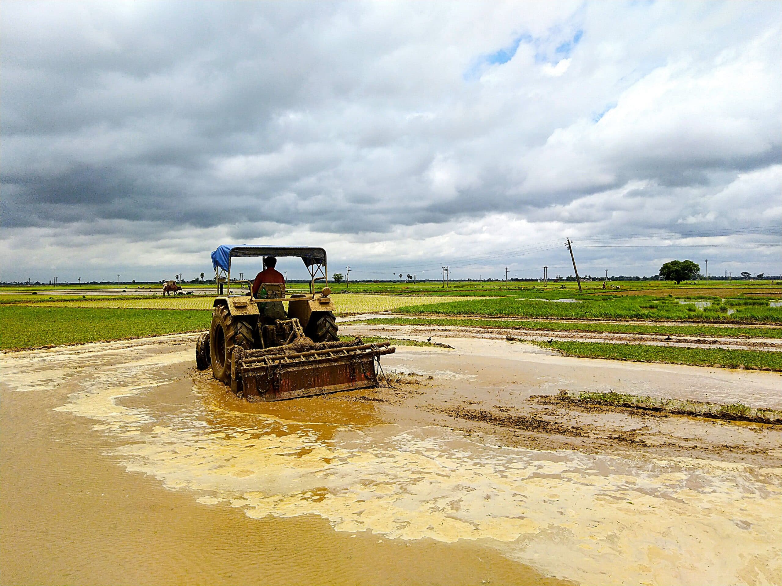Tractor working in a heavily flooded, muddy paddock demonstrating extreme wet soil conditions